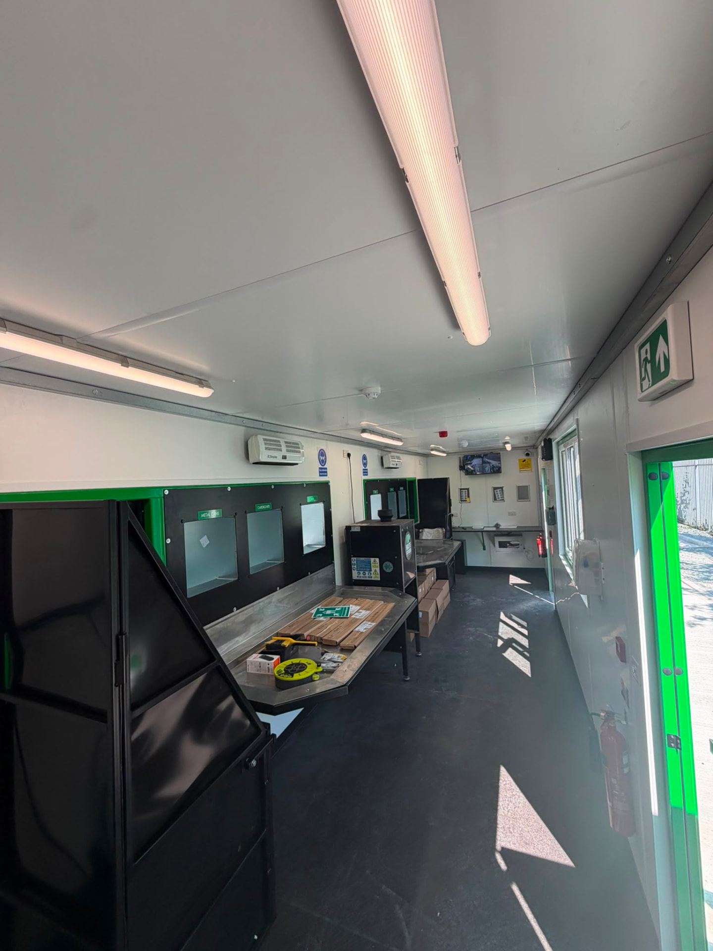 Interior of the recovery unit showing labelled segregation chutes, stainless sorting bench and monitoring screen